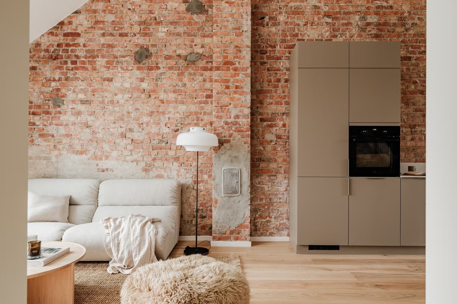Exposed brick wall and integrated kitchen in the Living Under the Sky attic apartment in Oslo by IK-architects